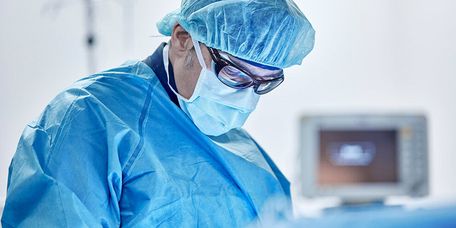 Innere Medizin Arzt mit Maske und Haube operiert einen Herzpatienten